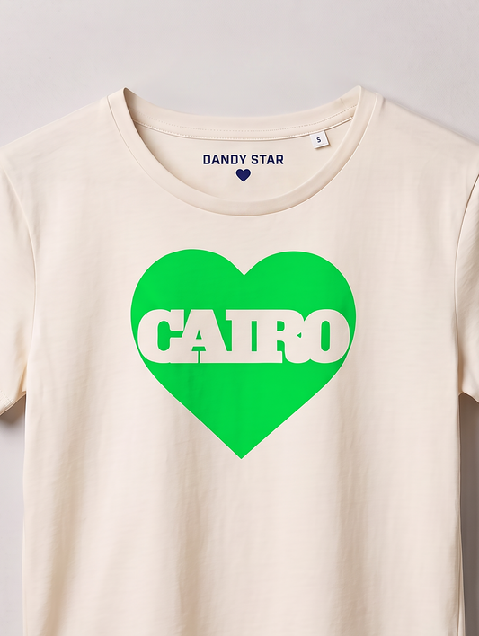 An off-white crewneck t-shirt featuring a bright green heart graphic on the chest with the word 'CAIRO' printed in white across it. The inside collar shows the brand name 'DANDY STAR'.