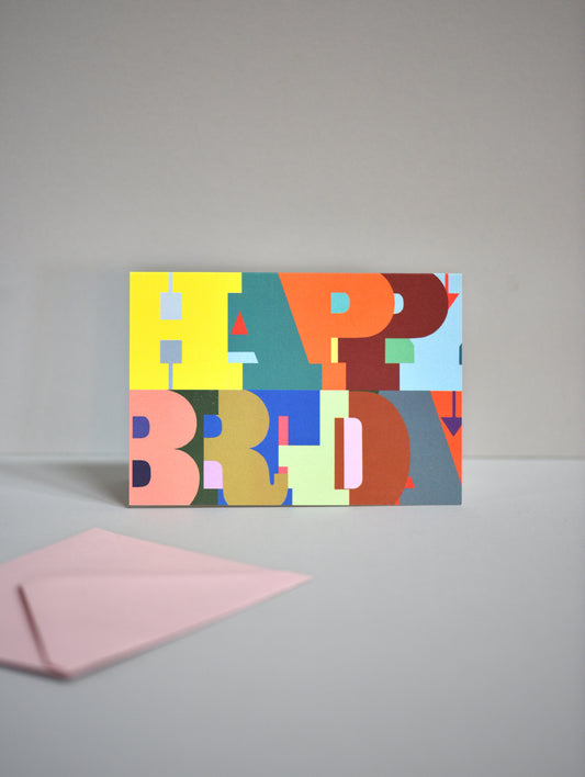 Colorful 'Happy Birthday' card with a pink envelope on a gray background