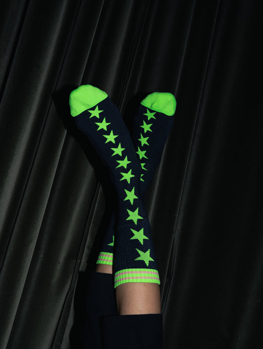 Black knee-high socks with green stars and cuffs on a black background
