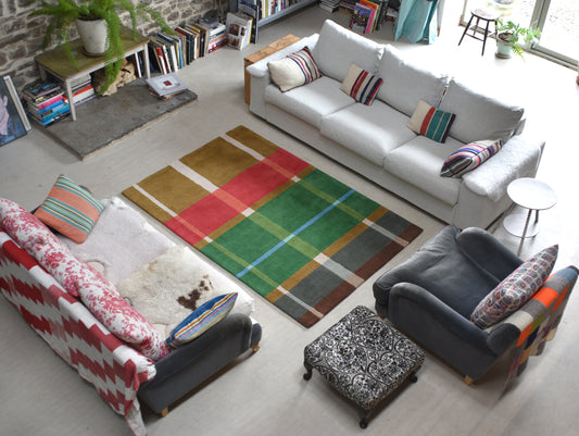 Living room with a colorful plaid rug, white sofa, and patterned cushions.