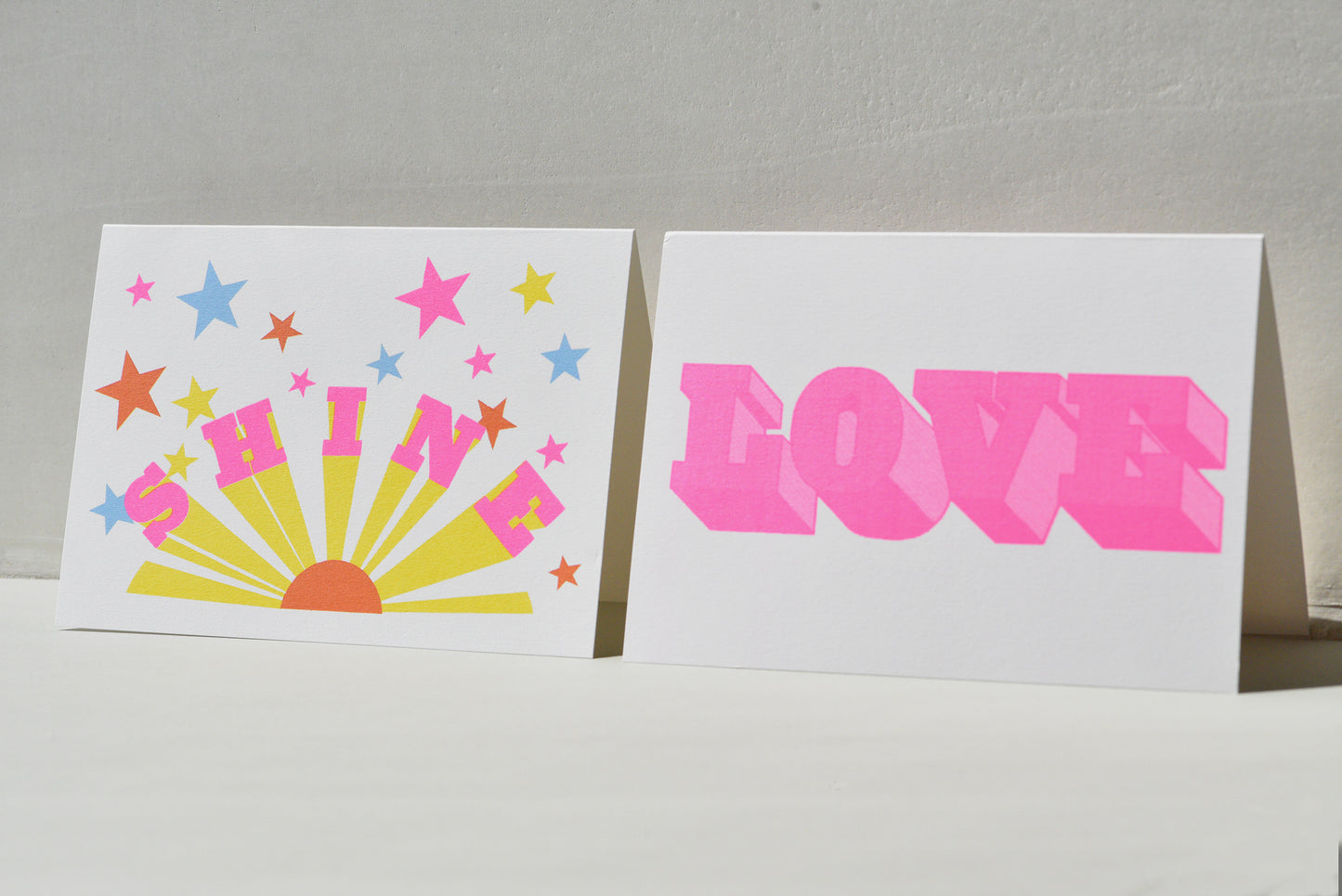Two greeting cards with colorful designs on a gray background