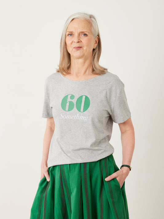 Woman wearing a gray t-shirt with '60 Something' text and green skirt on a white background