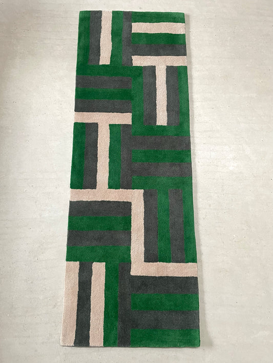 Geometric patterned rug with green, gray, and beige colors on a light gray background