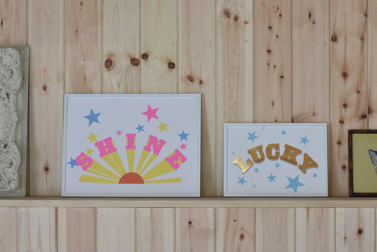 Decorative signs with 'SHINE', 'LUCKY', and star designs on a wooden shelf.