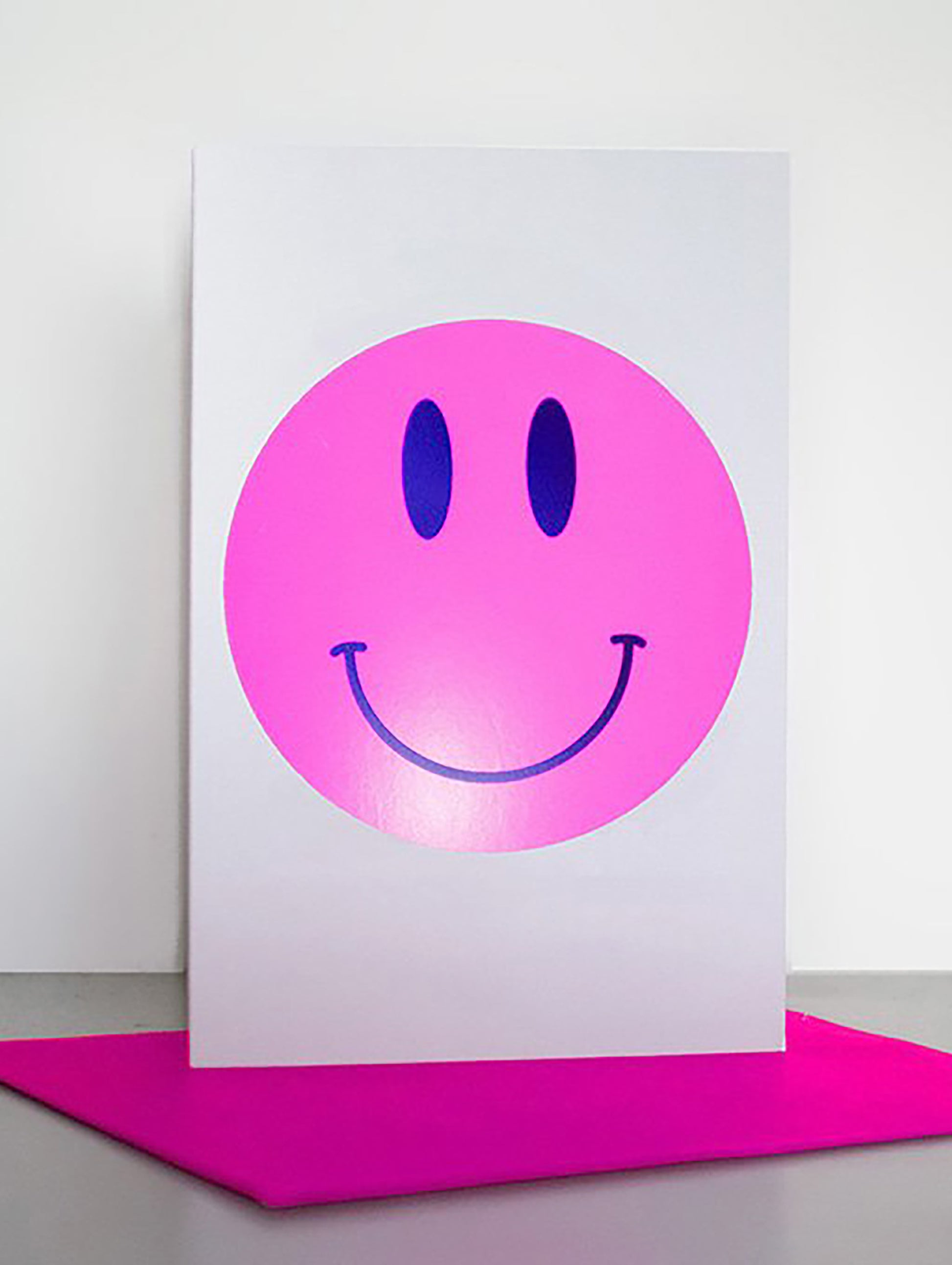 Pink smiley face on a white card with a pink base