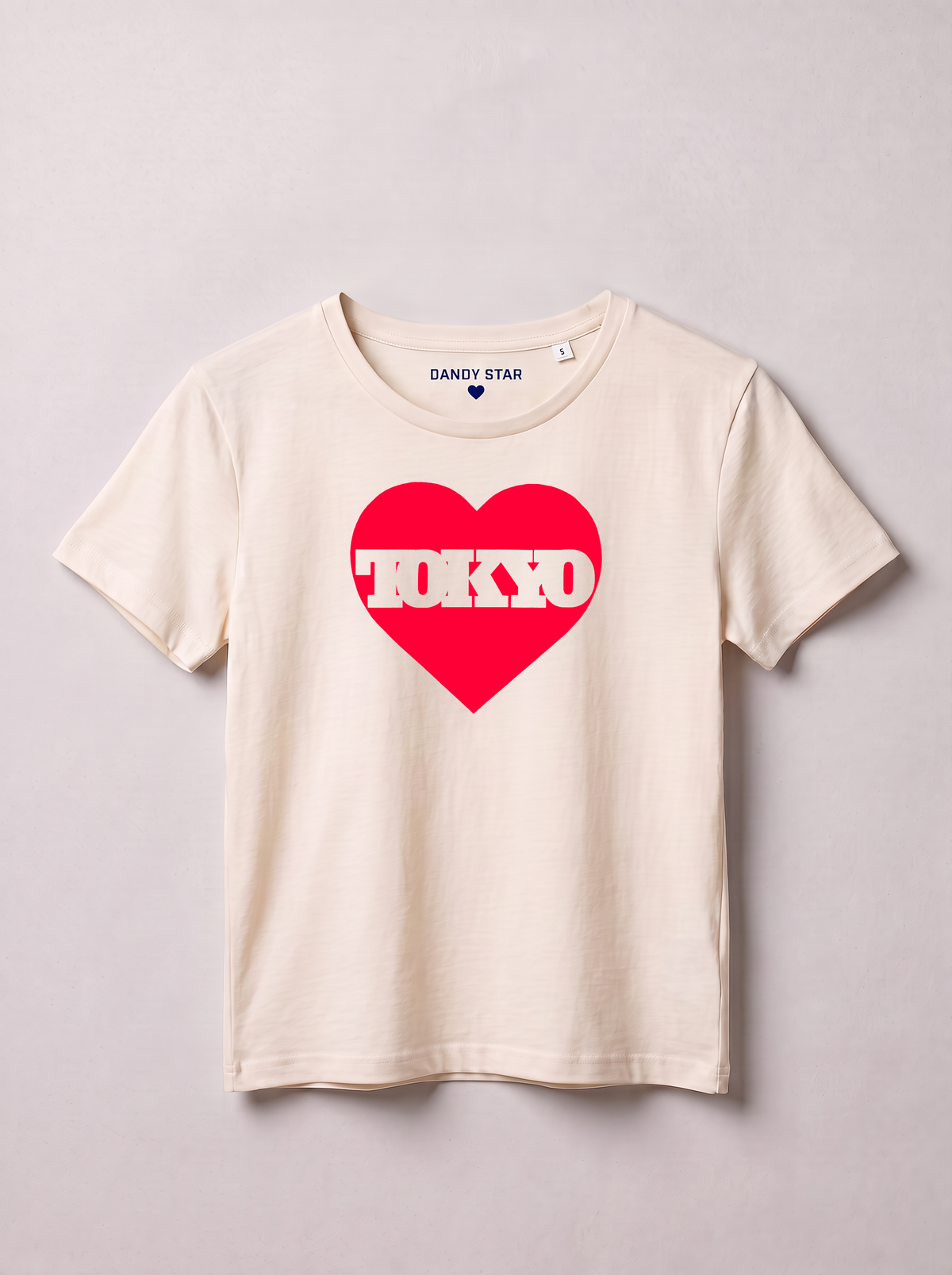 A cream-colored short-sleeve t-shirt with a red heart graphic on the chest containing the word 'TOKYO' in white. The inner neck label shows the brand 'DANDY STAR'.