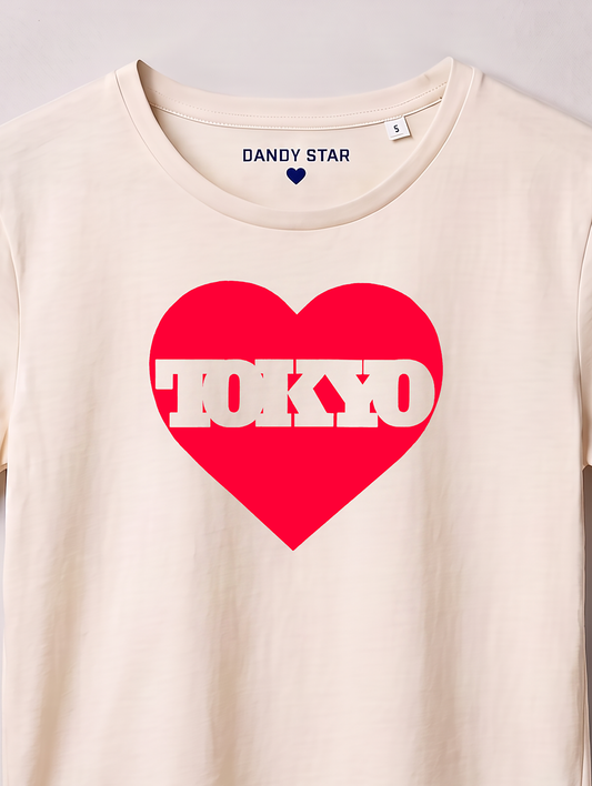 An off-white crewneck t-shirt featuring a large red heart graphic on the chest with the word 'TOKYO' printed in white inside it. The inside collar shows the brand name 'DANDY STAR'.