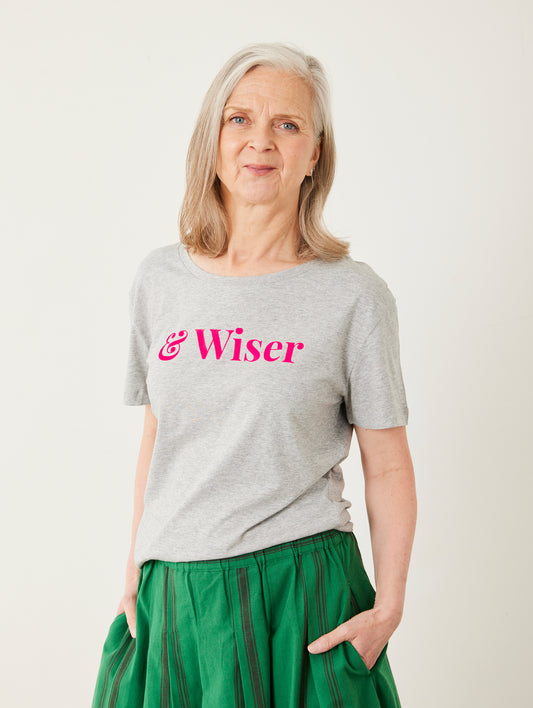 Woman wearing a gray t-shirt with 'Wiser' printed in pink on a white background