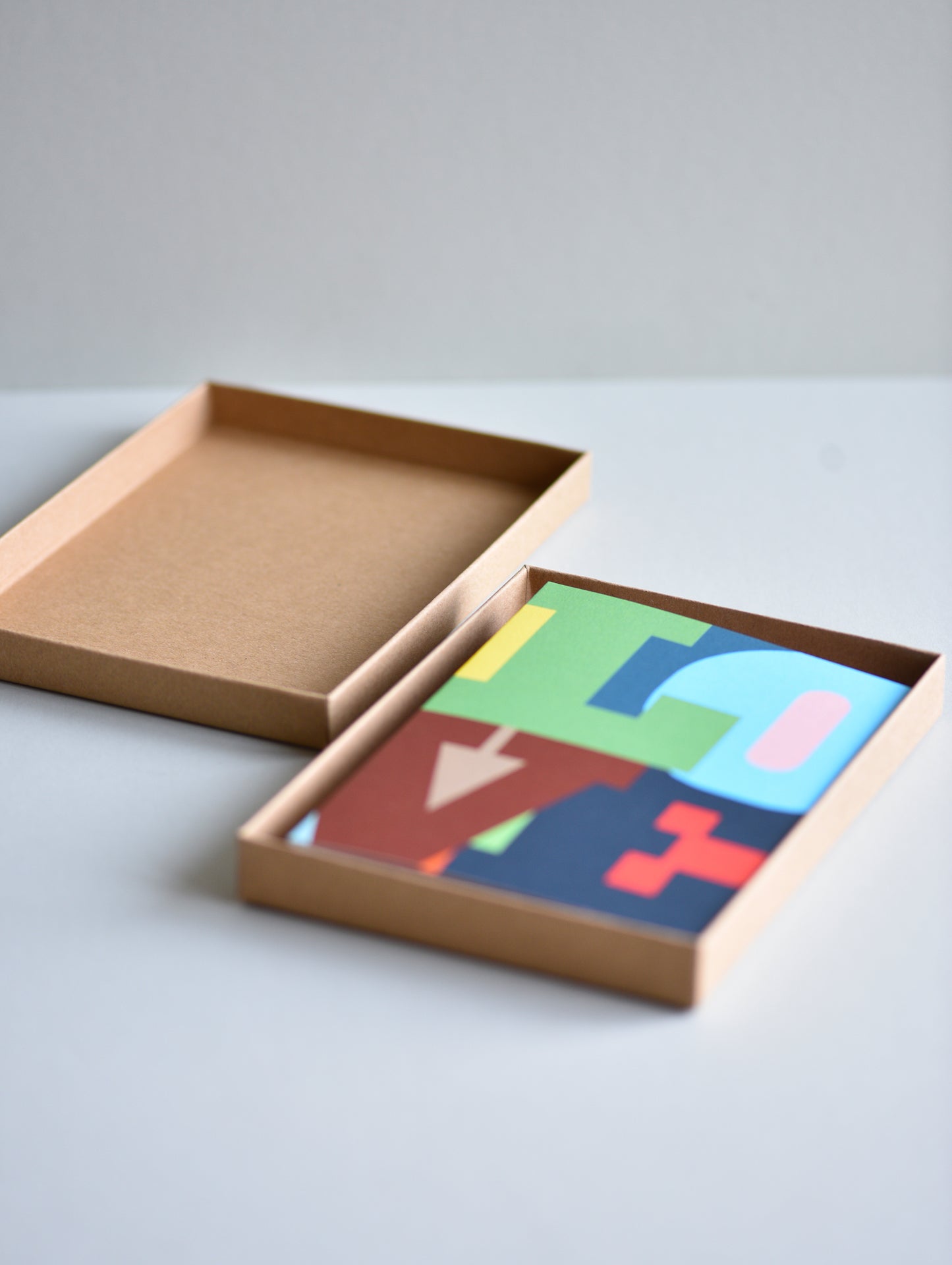 Colorful geometric shapes in a cardboard box on a light gray background