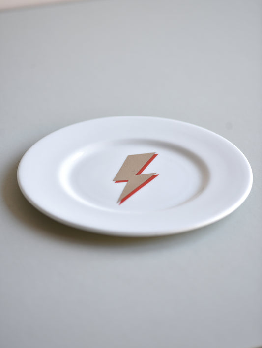 White plate with a red lightning bolt design on a light gray background