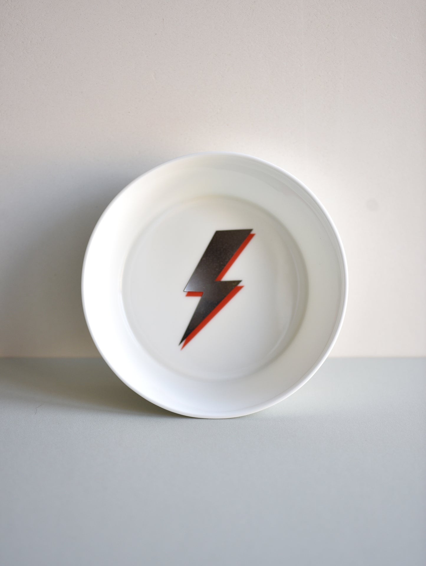 White plate with a red and black lightning bolt design on a white background