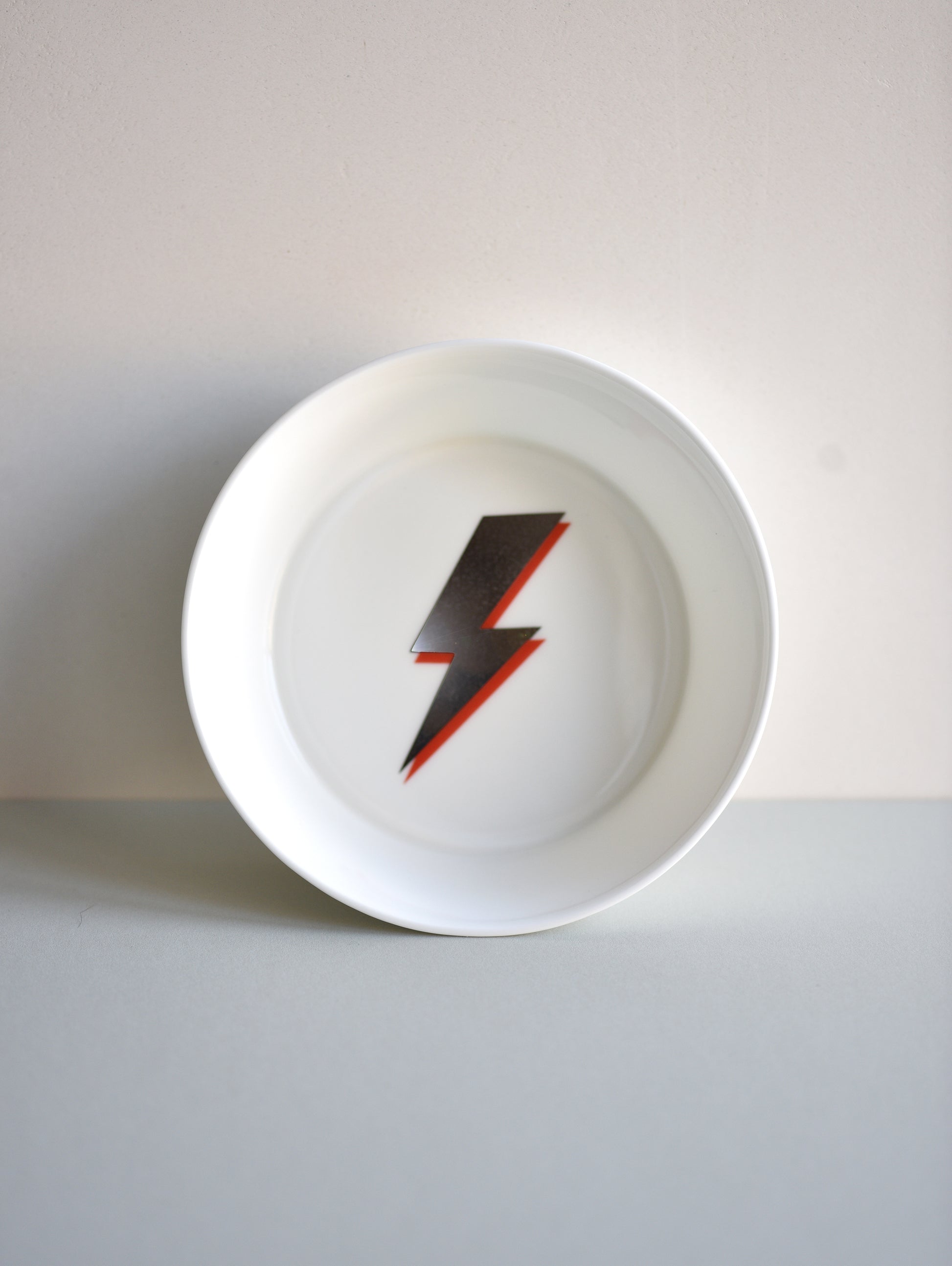 White plate with a red and black lightning bolt design on a white background