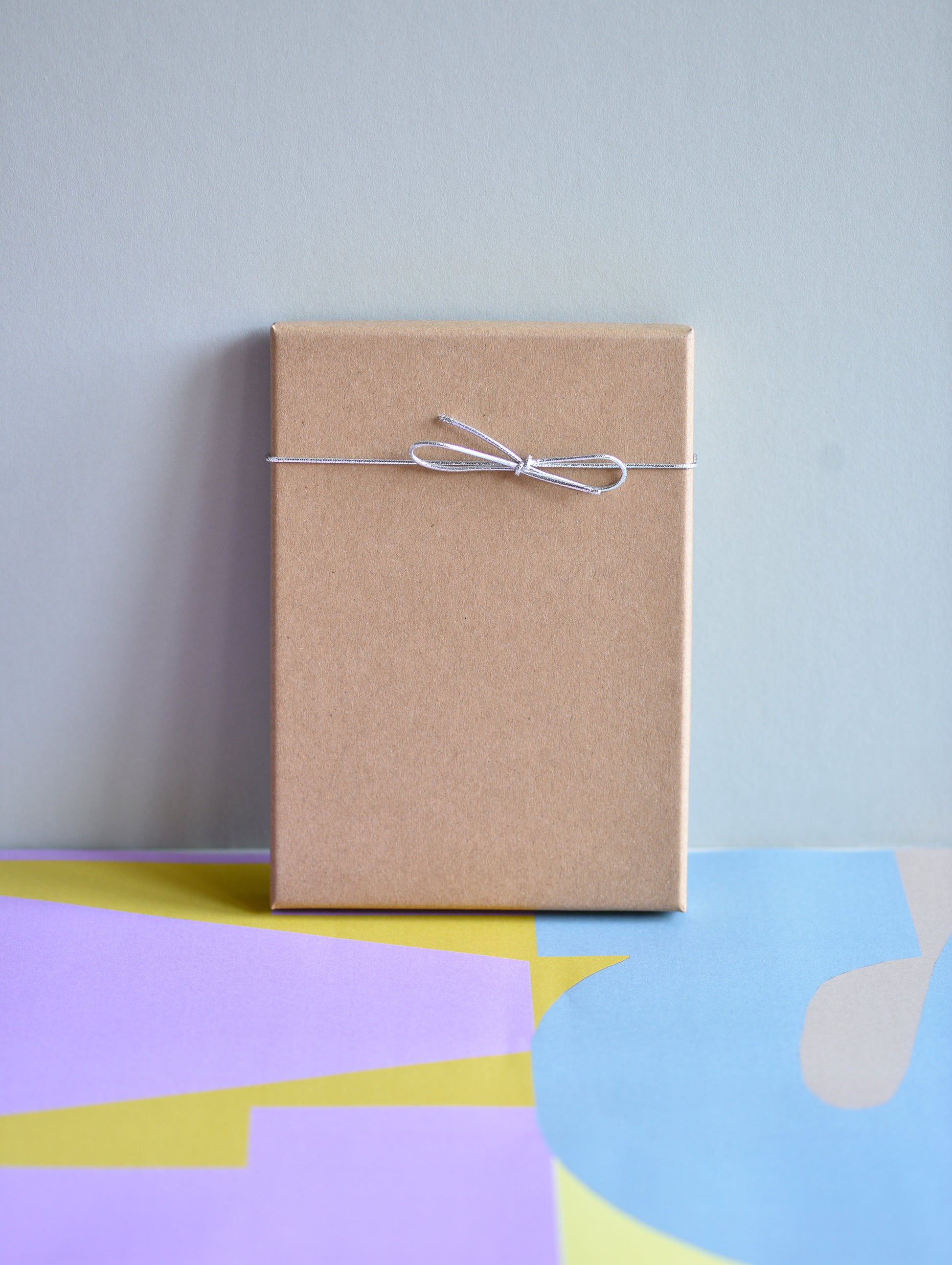 Brown paper package tied with string on a colorful abstract background