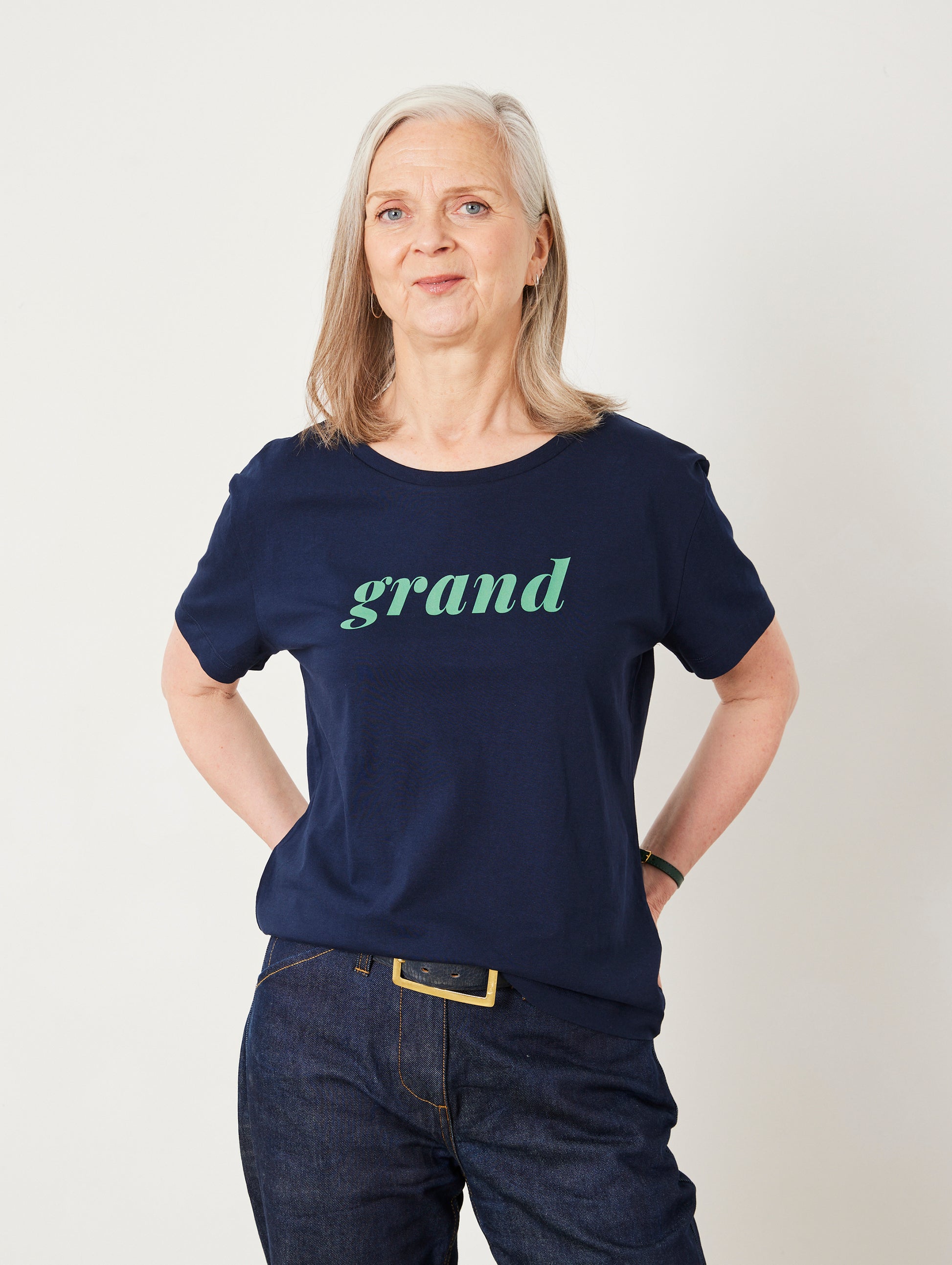 Woman wearing a navy blue t-shirt with 'grand' printed on it against a white background