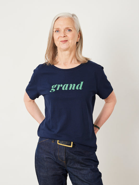 Woman wearing a navy blue t-shirt with 'grand' printed on it against a white background