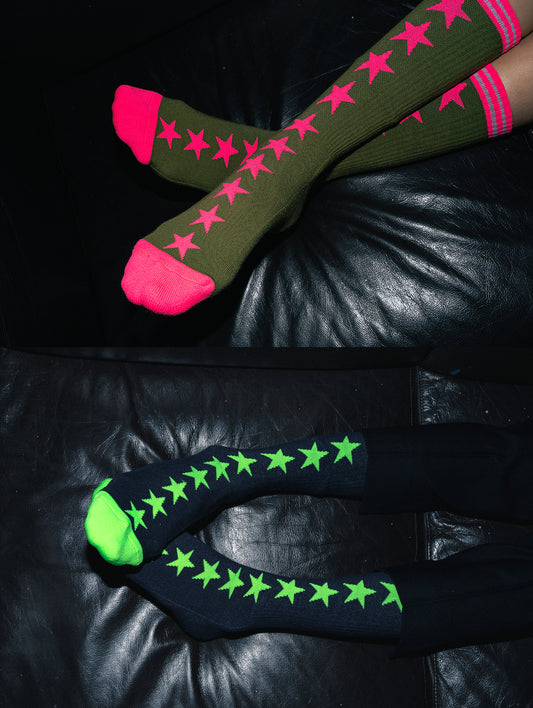Green socks with pink stars on a black leather surface