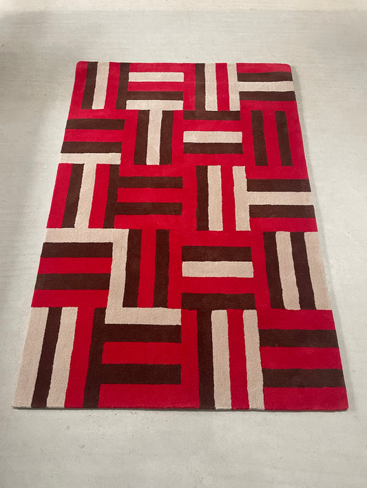 Geometric patterned rug with red, brown, and beige colors on a plain background
