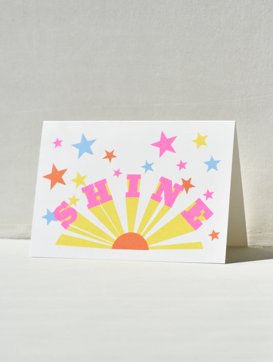 Greeting card with 'SHINE' and colorful stars on a white background
