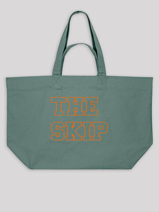 Green tote bag with 'THE SKIP' text in orange on a light gray background