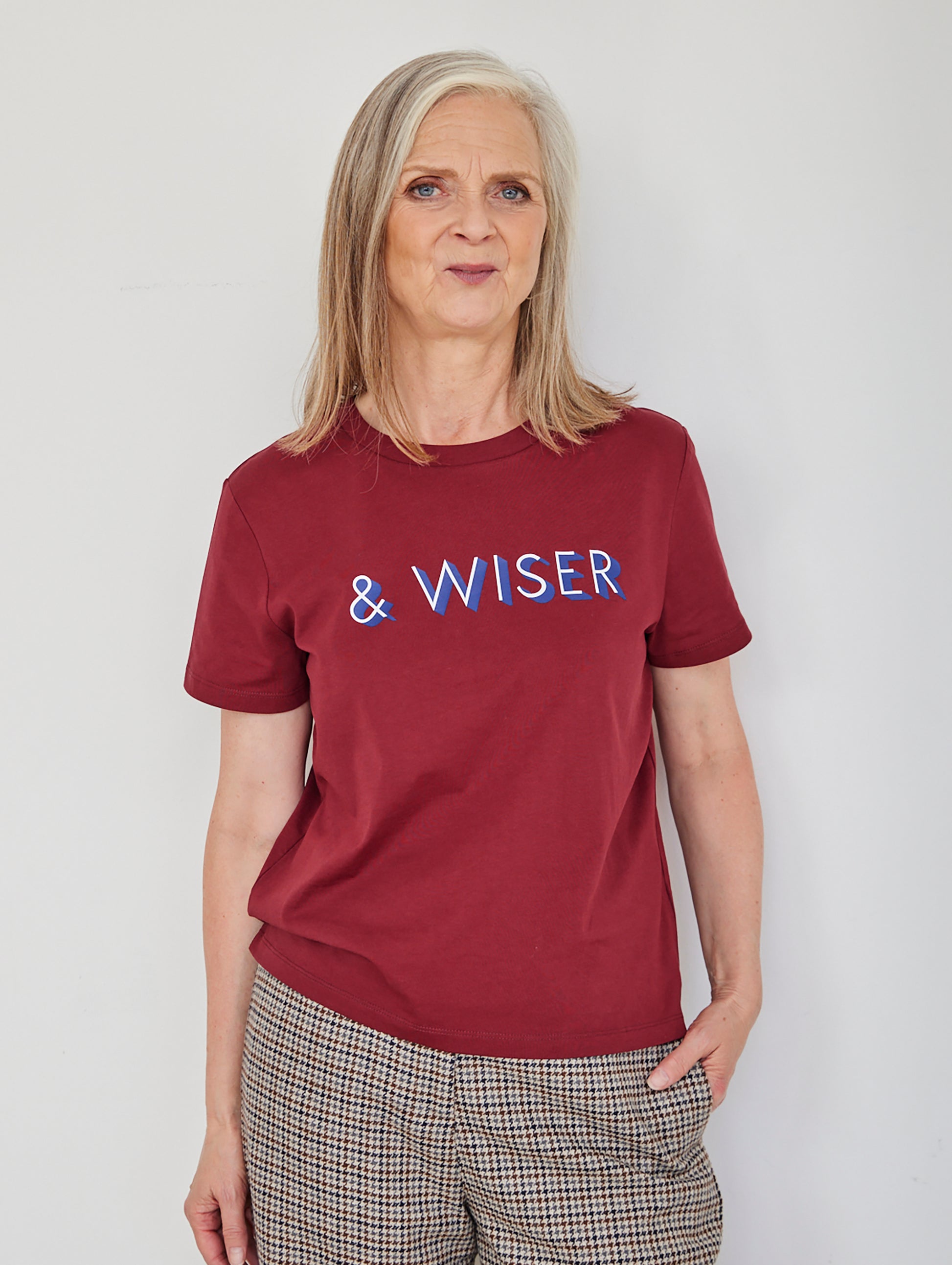 Alyson Walsh wearing a maroon t-shirt with 'WISER' text on a plain background