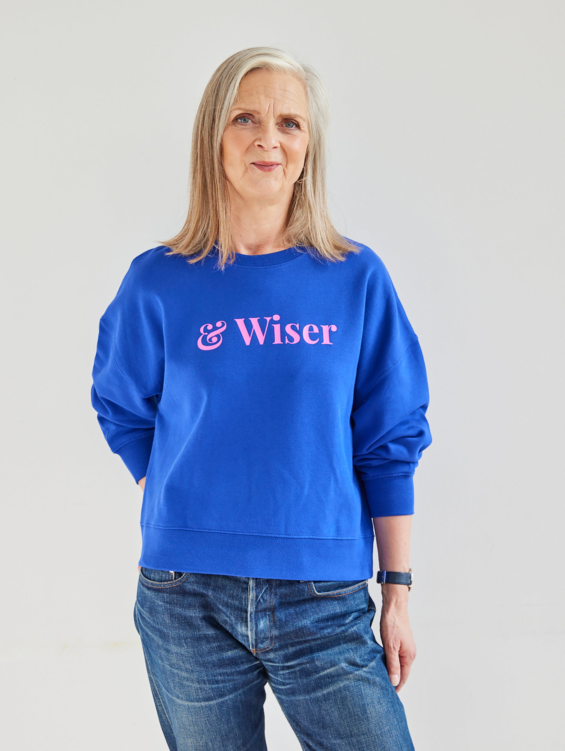 Alyson Walsh wearing a blue sweatshirt with 'Wiser' text on a plain background