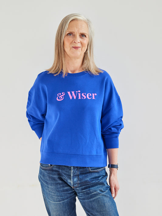 Alyson Walsh wearing a blue sweatshirt with 'Wiser' text on a plain background